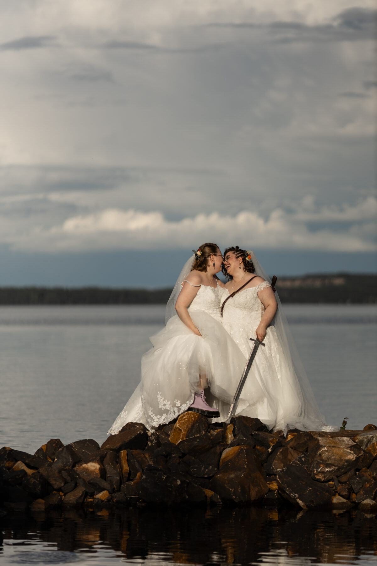 queer couple in wedding dresses standing on the rocks